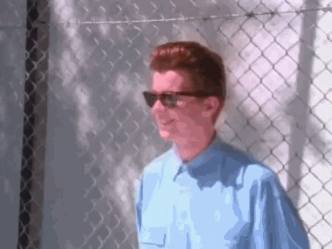 Scen från musikvideon Never Gonna Give You Up där Rick Astley dansar framför ett stängsel.