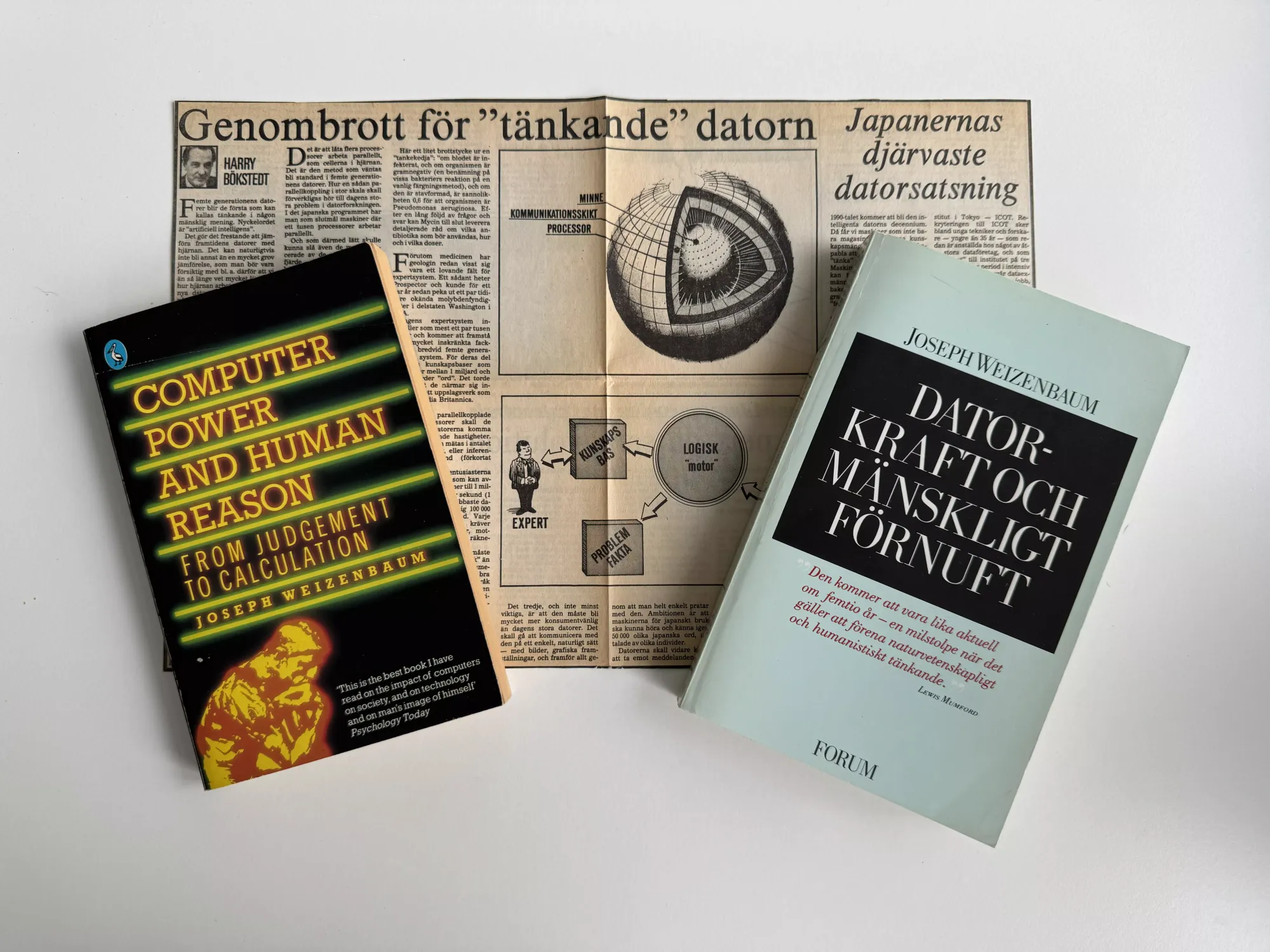 Mina exemplar av boken, en på engelska och en på svenska, och tidningsurklippet i bakgrunden.