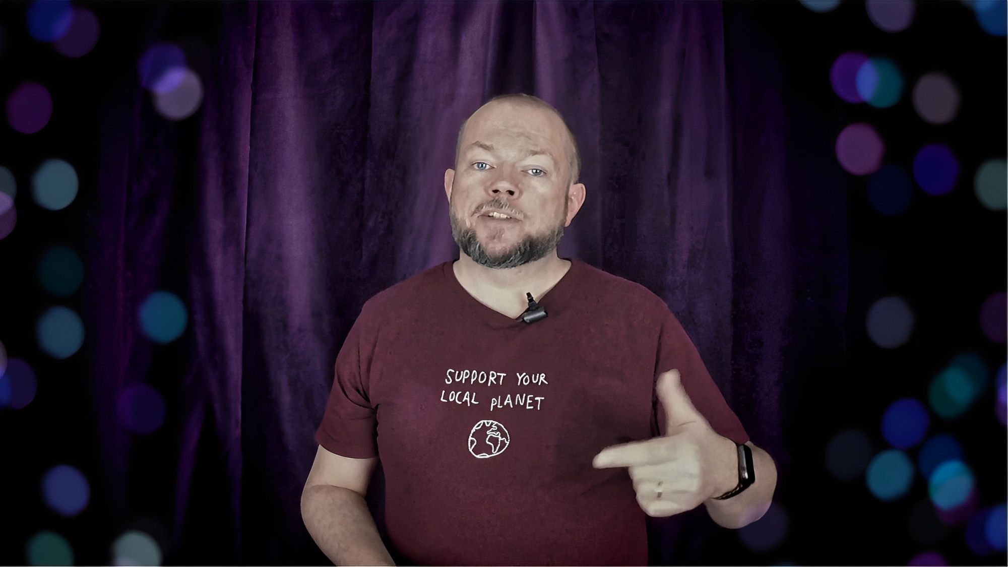 Per Axbom föreläser mot en lila bakgrund. Hans röda t-shirt har texten ”Support your local planet”.